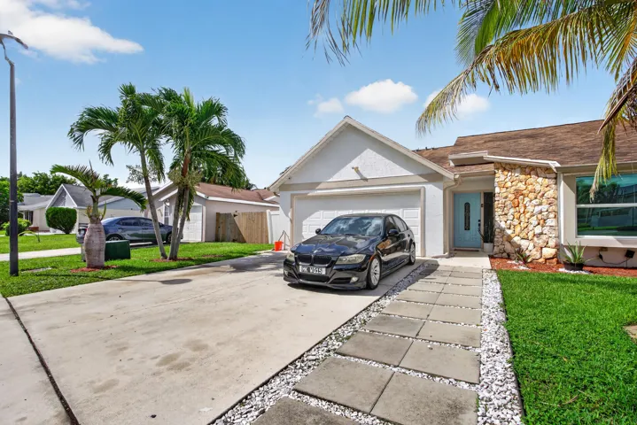 Single-story residence featuring a two-car garage, stone facade accents, and a distinctive light blue entry door