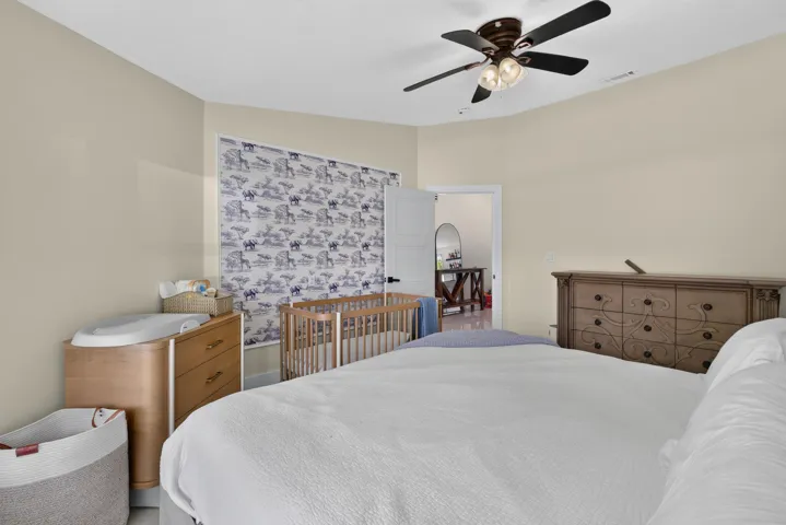 Spacious room featuring light-colored walls, a ceiling fan with integrated lighting, and a patterned wall covering