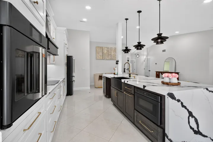 Contemporary kitchen featuring an oversized island with a waterfall edge, integrated microwave, and farmhouse sink