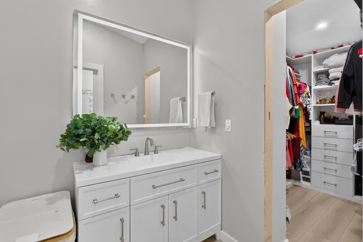 White vanity with an integrated sink, brushed nickel faucet, and a large illuminated mirror