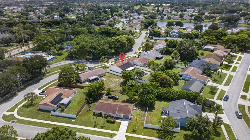 Aerial overview of a residential neighborhood featuring single-story homes with shingle roofs and surrounding mature trees