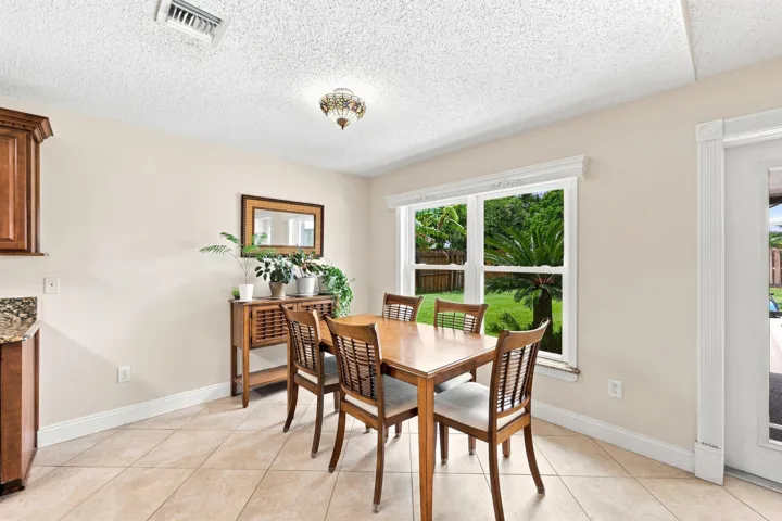 Dining area featuring a large window, tiled flooring, wood cabinetry, and a granite-finish countertop