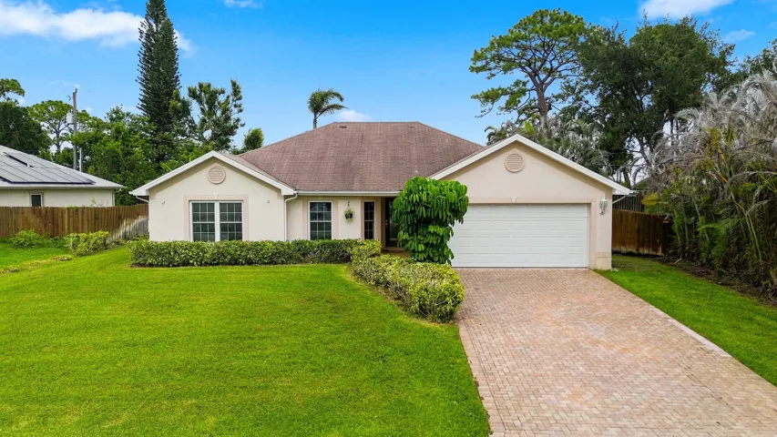 Single-story residence featuring a two-car garage, light-colored exterior finish, and a brick paver driveway