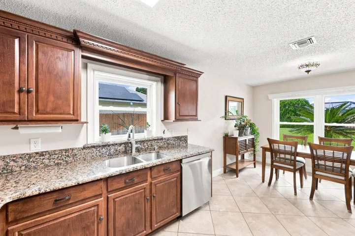 Kitchen featuring wood cabinetry with decorative molding, granite countertops, and a double basin stainless steel sink