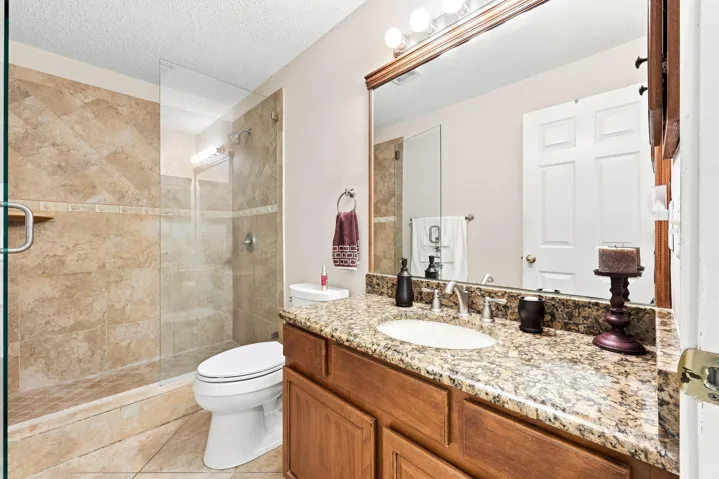 Bathroom featuring a walk-in shower with glass enclosure, natural stone tile, and a built-in shower niche