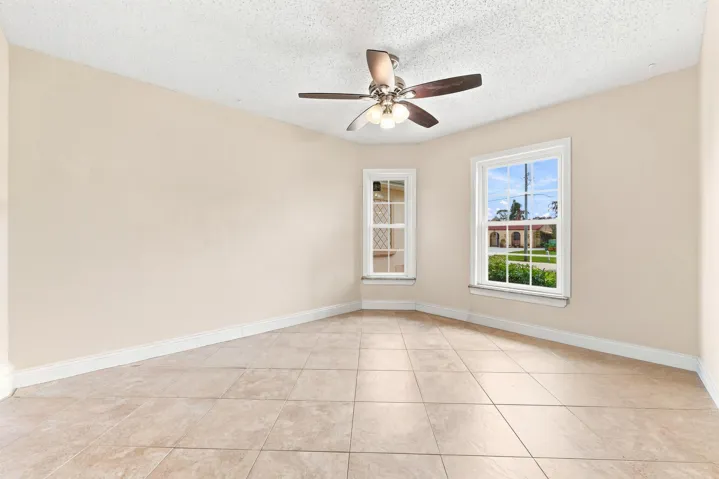 Spacious interior featuring neutral wall tones, large-format tile flooring, and multiple windows with white trim