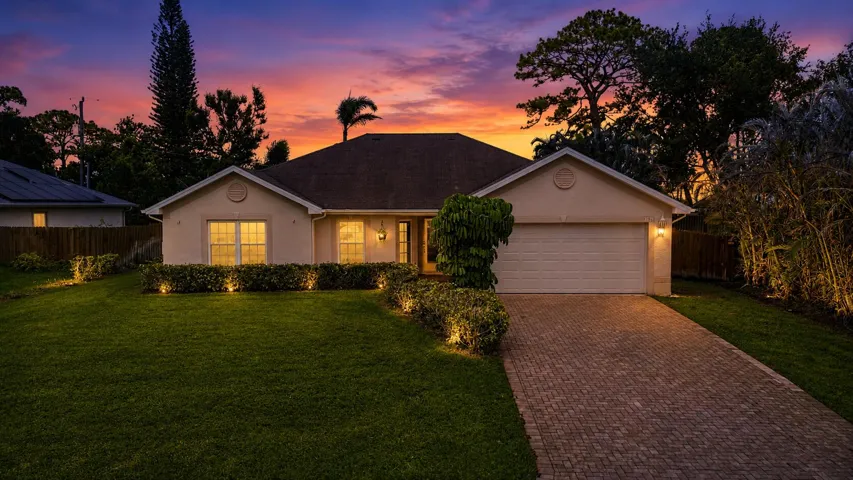 Single-story residence featuring a paved driveway, a two-car garage, and a lush green lawn