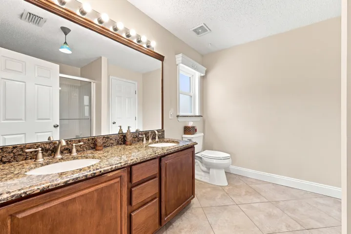 Dual sink vanity with a granite countertop and wood-finish cabinetry