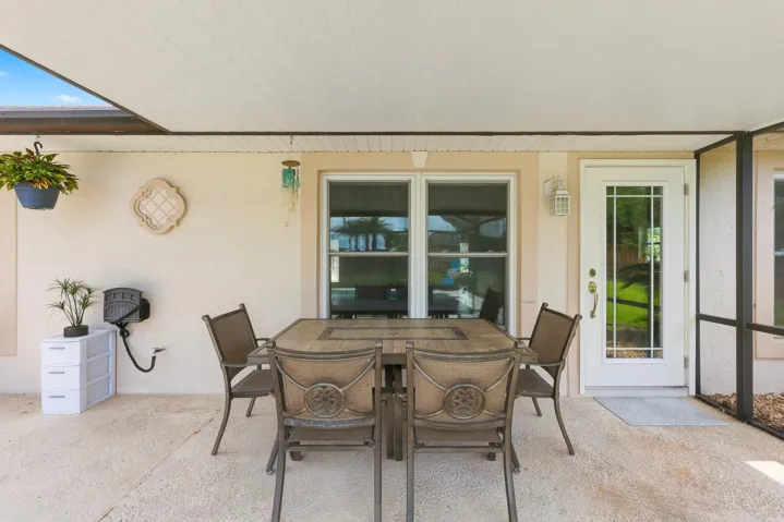 Covered patio featuring a textured concrete slab, a white paneled ceiling, and a full-light glass panel door