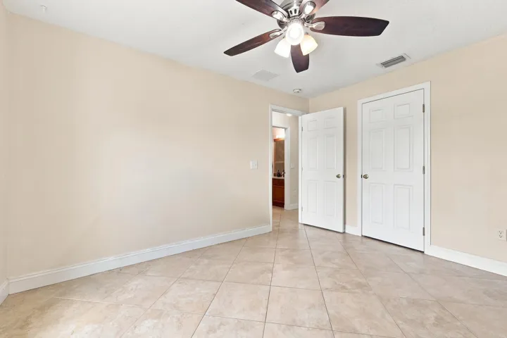 Neutral-toned interior room featuring large format tile flooring and a ceiling fan with light fixture
