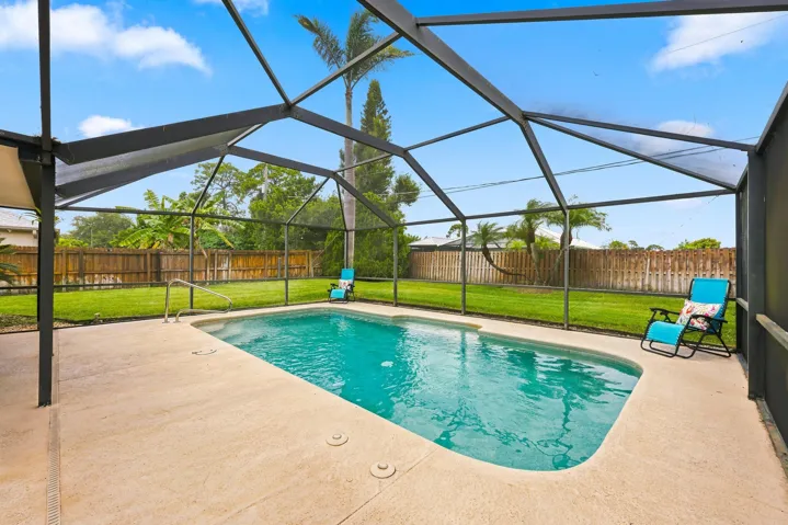 Screened swimming pool enclosure with a light-colored concrete deck