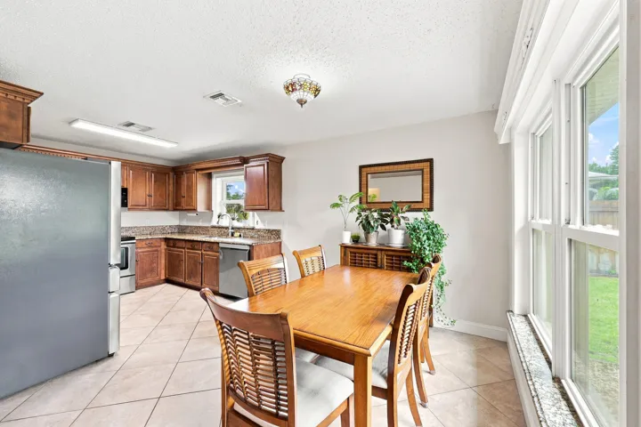 Kitchen and dining area featuring wood cabinetry, stainless steel appliances, granite countertops, and ceramic tile flooring