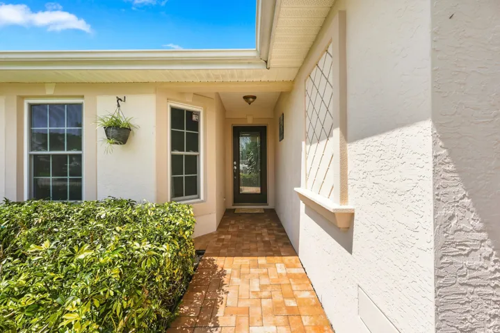 Brick paver walkway leading to a recessed entryway with a glass-paneled door