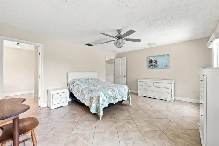 Spacious room featuring neutral tone flooring, light neutral wall paint, and a ceiling fan with integrated lighting