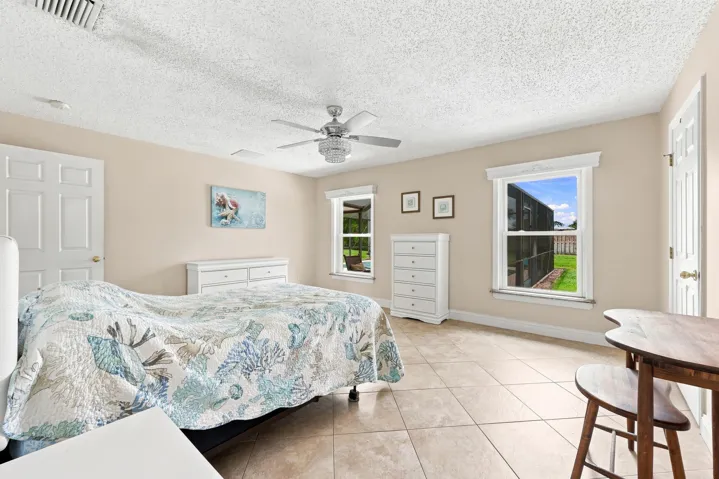 Spacious room featuring tile flooring, neutral wall tones, two paneled doors, and two windows with white trim
