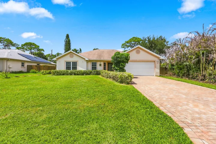 Single-story residence featuring a neutral stucco exterior, a two-car garage, and a paver driveway