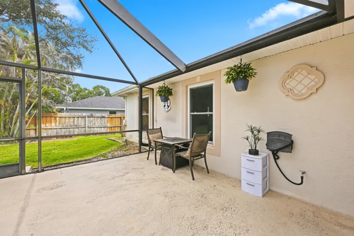 Screened lanai featuring a concrete patio, exterior wall with a decorative accent, and a clear view of the fenced backyard