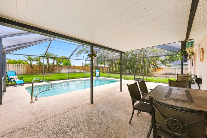 Screened-in pool and patio area featuring a concrete deck and a covered dining space