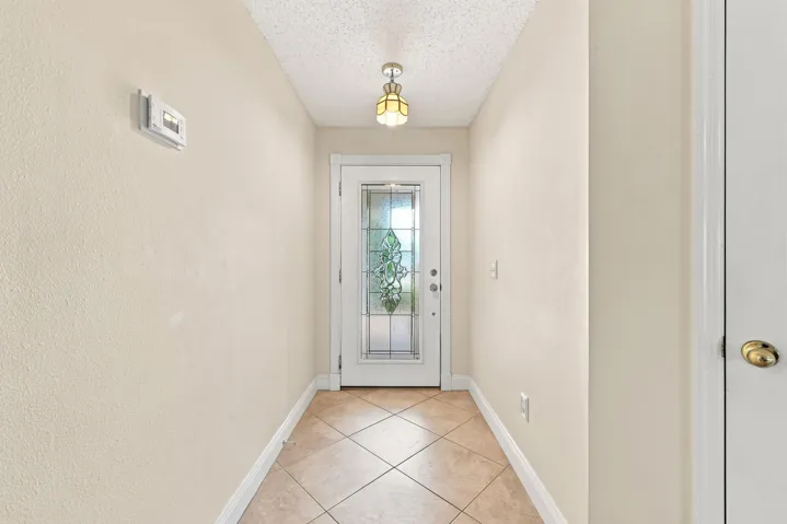Entryway featuring neutral-toned walls, diagonal tile flooring, and a decorative glass door