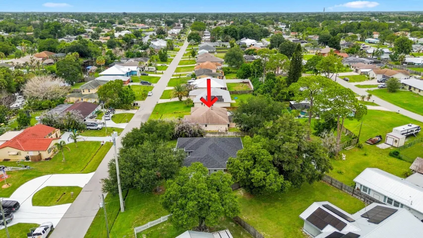 Aerial perspective highlighting a residential neighborhood with numerous single-story homes, mature trees, and manicured lawns