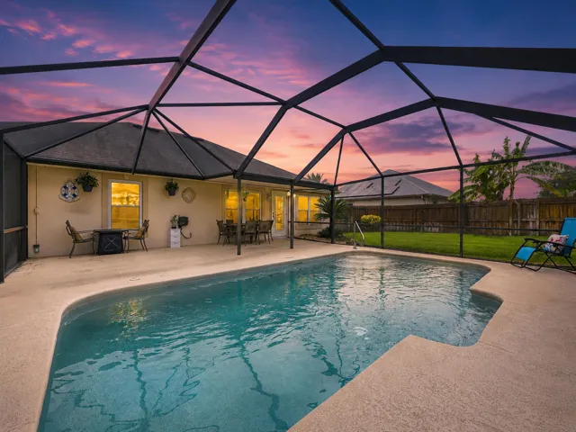 Screened-in pool enclosure featuring a concrete deck and a rectangular swimming pool