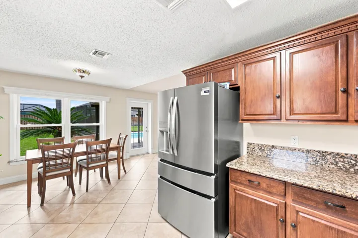 Kitchen featuring wood cabinetry, stone countertops, and a stainless steel refrigerator