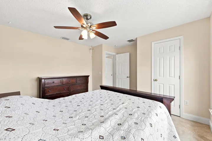 Interior room featuring a ceiling fan with integrated lighting, neutral wall paint, white trim, and light-toned tile flooring