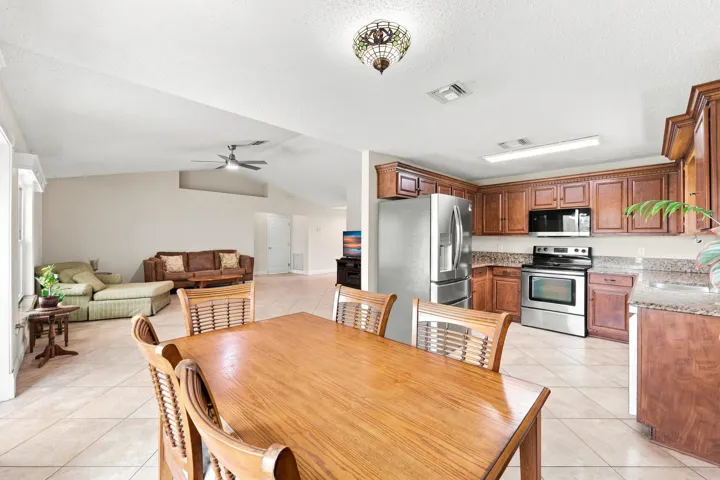 Spacious kitchen featuring wood cabinetry, stainless steel appliances, and granite-finish countertops