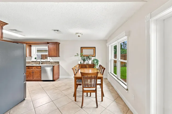 Kitchen and dining area featuring warm wood cabinetry, stone countertops, and stainless steel appliances
