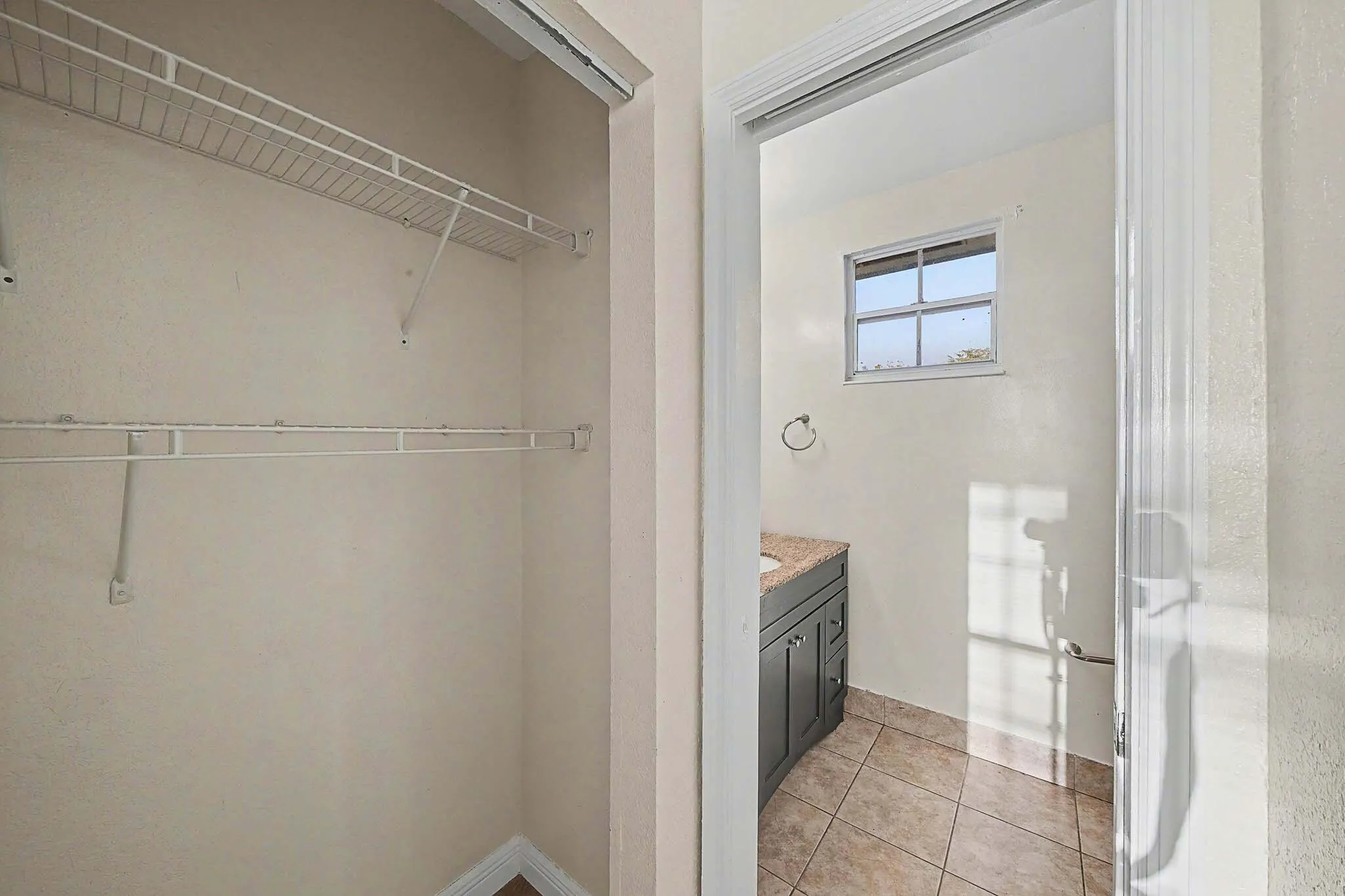 Bright bathroom featuring a window, tile flooring, and a vanity with a stone countertop
