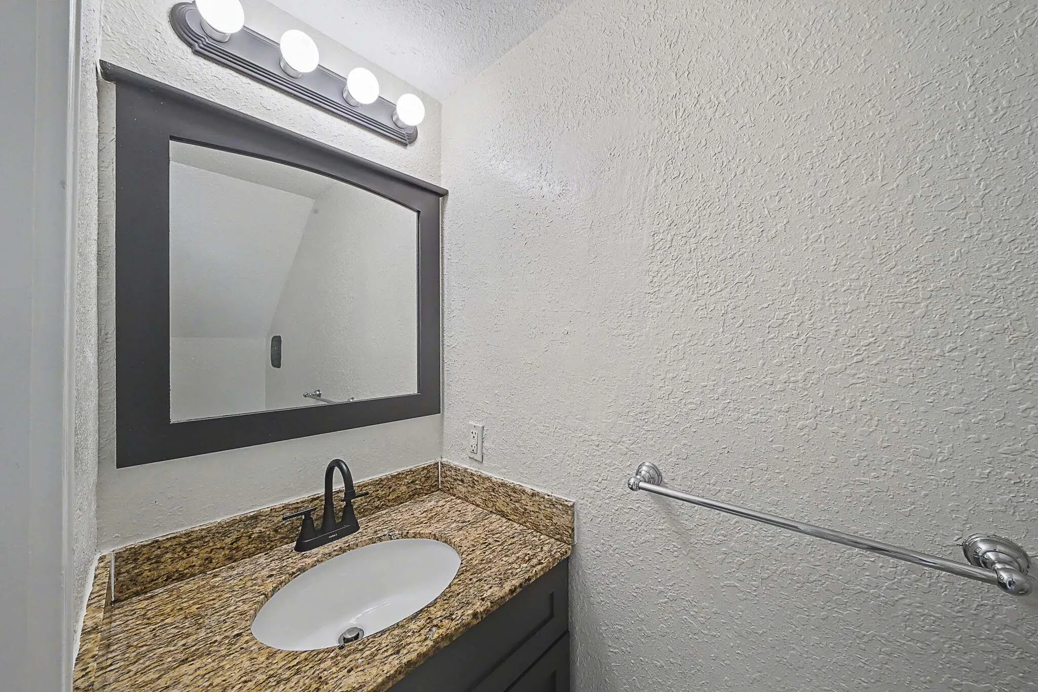 Vanity with a granite-style countertop, undermount sink, and matte black faucet