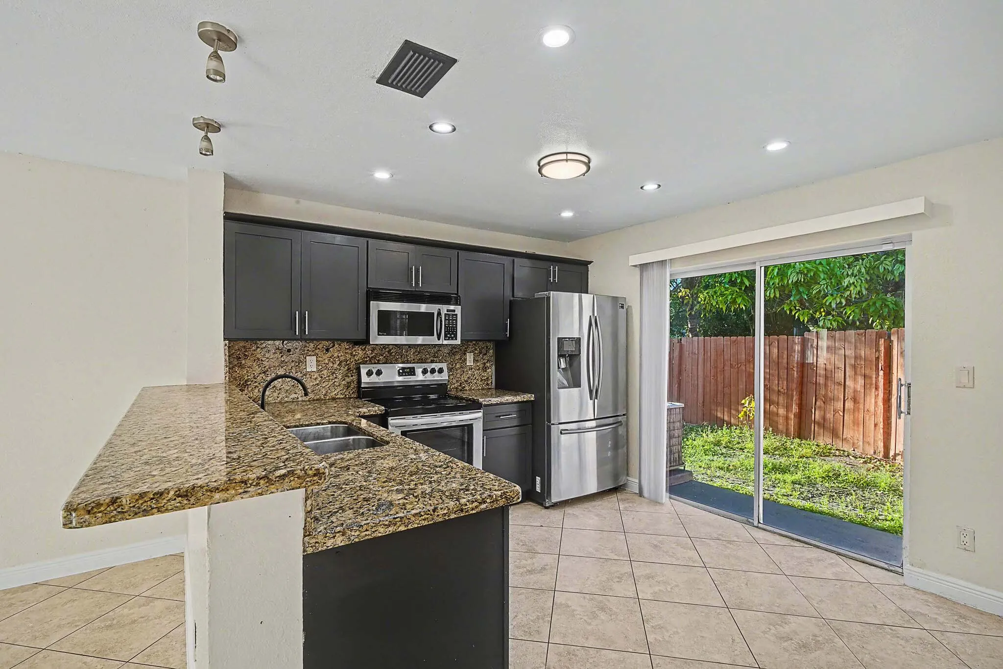 Kitchen featuring granite countertops, dark cabinetry, stainless steel appliances, and a breakfast bar