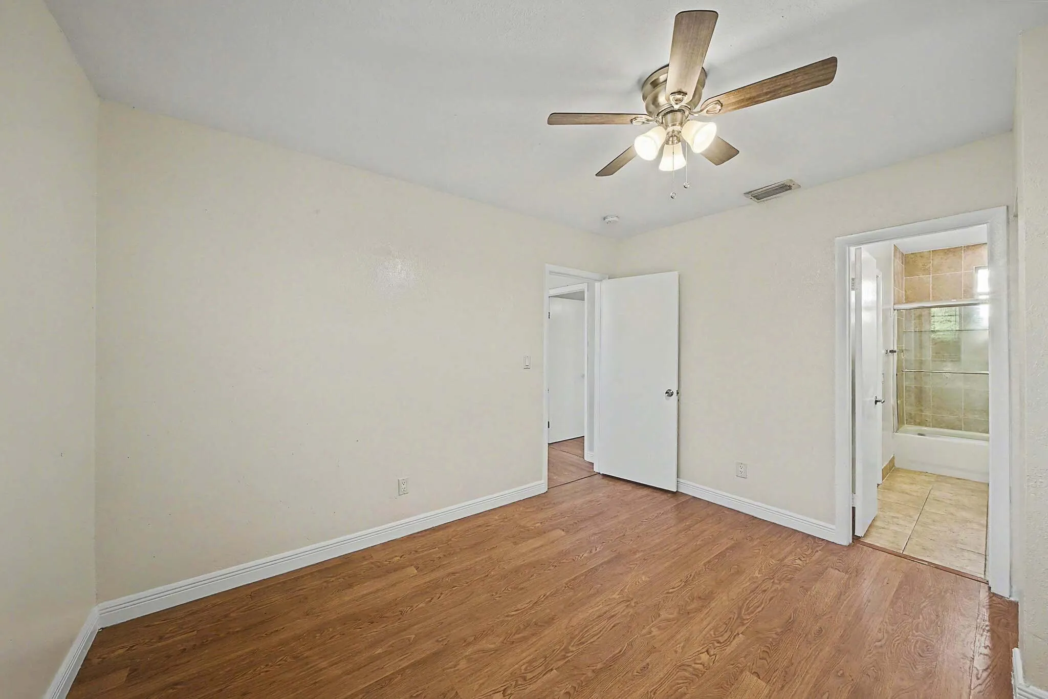Room featuring wood-finish flooring, a ceiling fan with integrated lighting, and light-toned walls