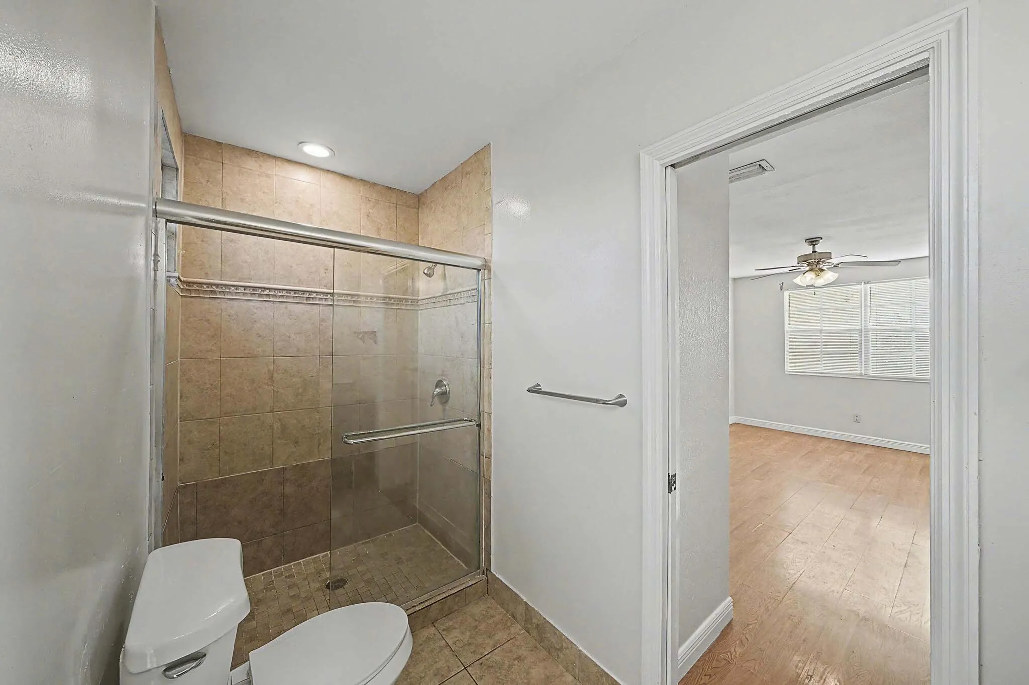 Bathroom featuring a tiled standing shower with a glass enclosure, a white toilet, and recessed lighting