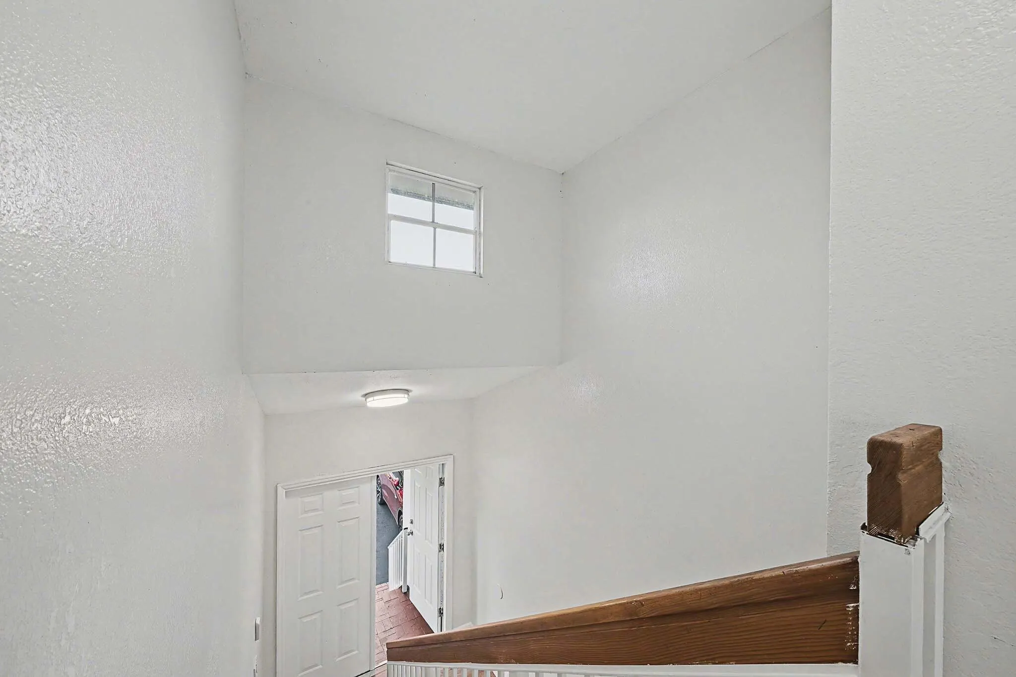 Stairwell featuring a white painted balustrade, wood-finish handrail, and high ceilings with a transom window