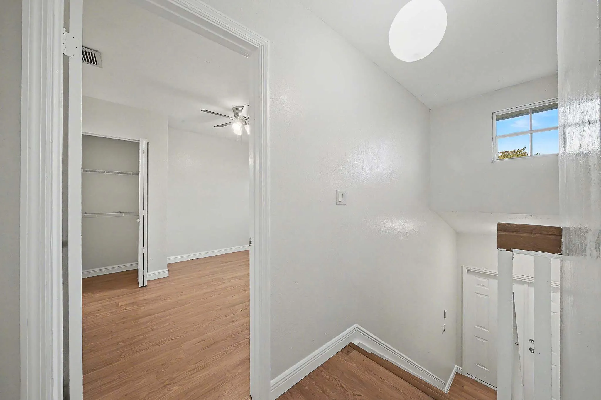 Interior hallway with wood-finish flooring and a white color palette