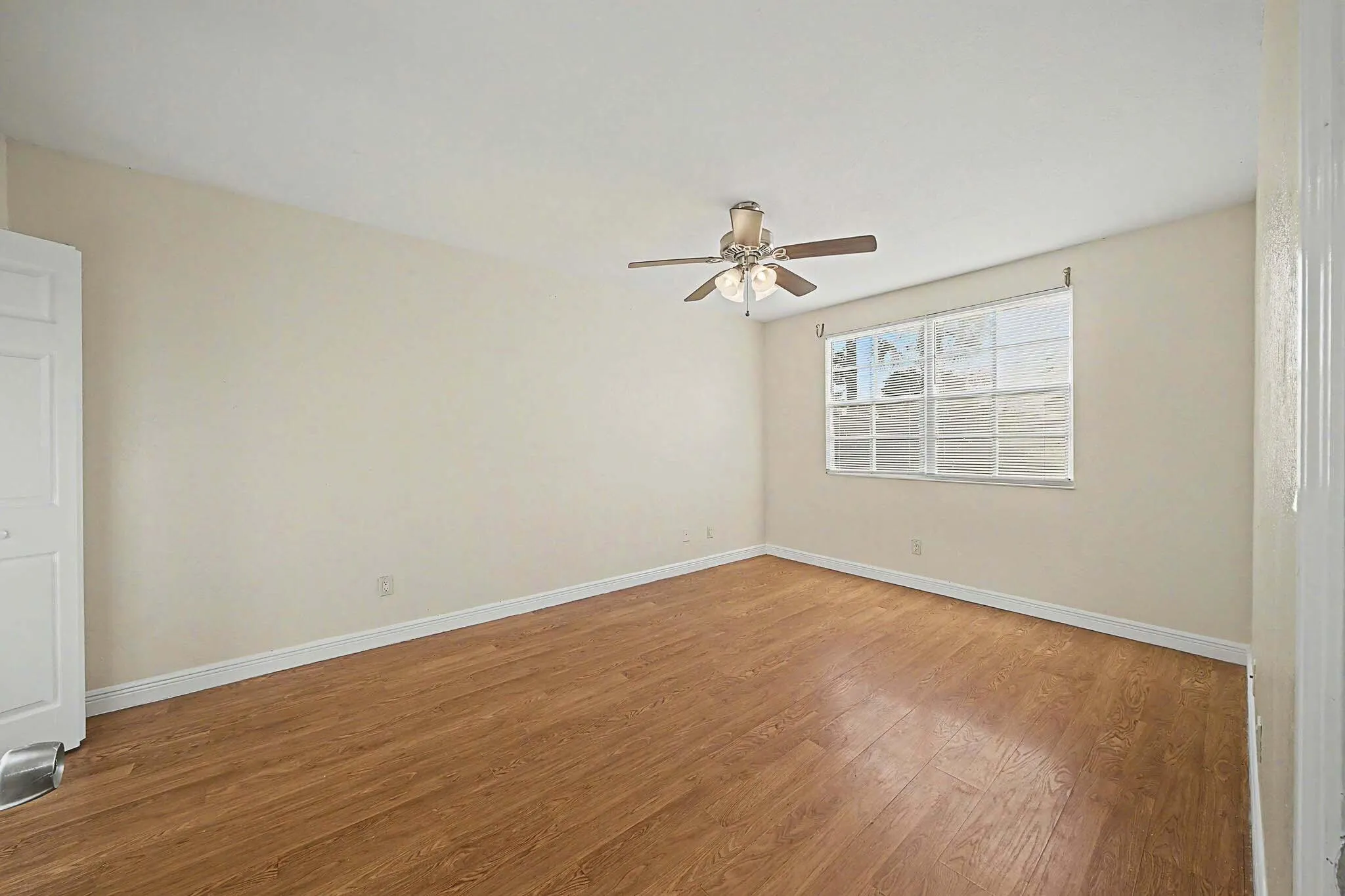 Bright interior room featuring wood-finish flooring, light-toned walls, and a ceiling fan with integrated lighting