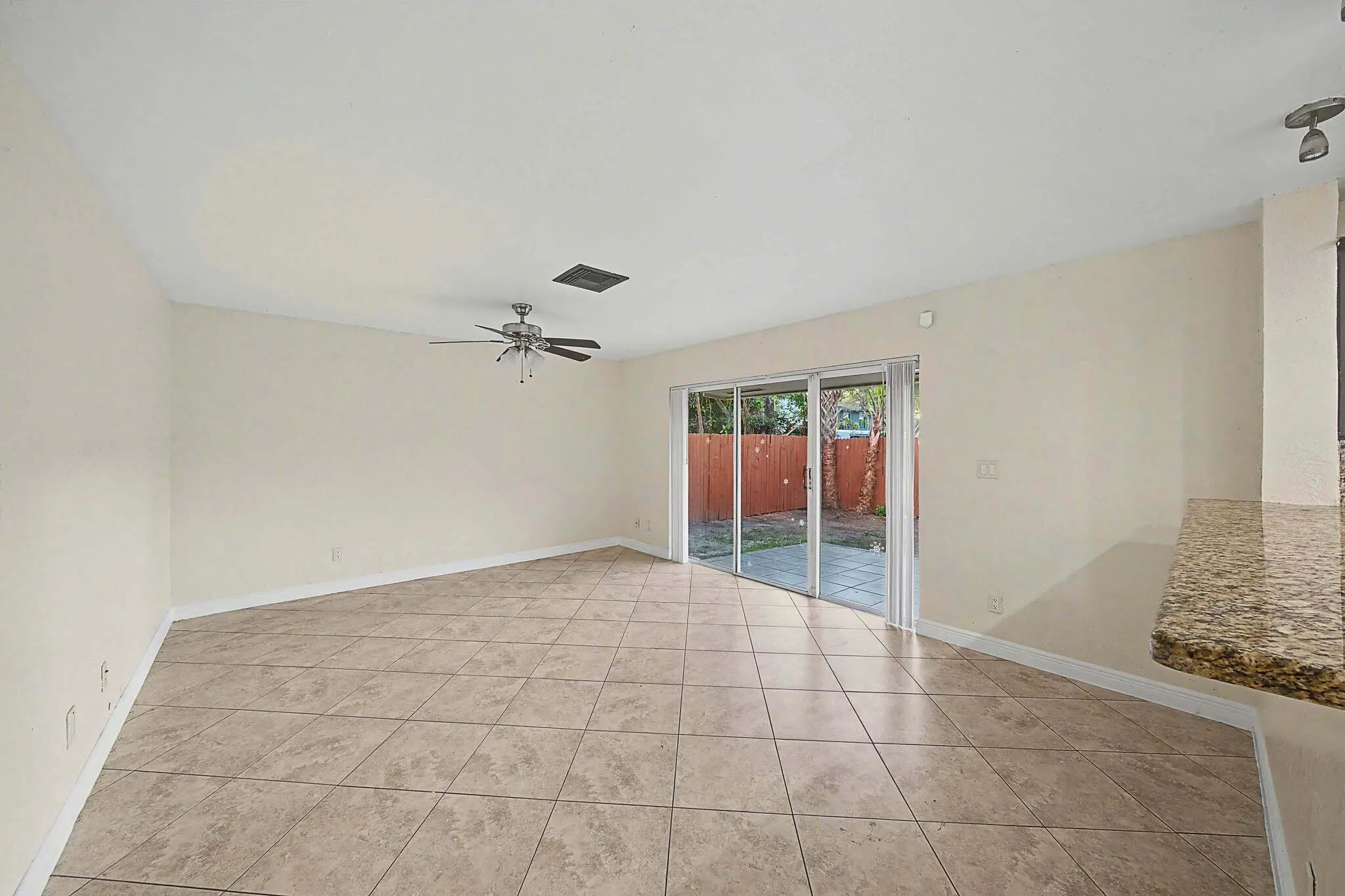 Expansive living area featuring large format tile flooring, a ceiling fan, and sliding glass doors leading to an exterior patio