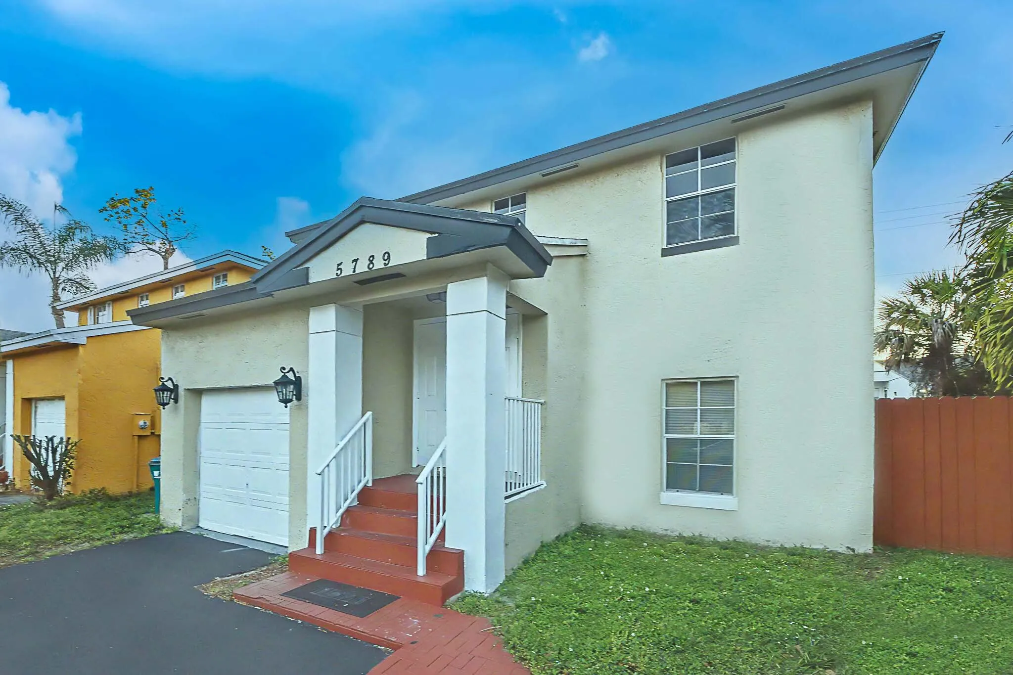 Contemporary stucco exterior with a prominent entrance featuring white columns and railings