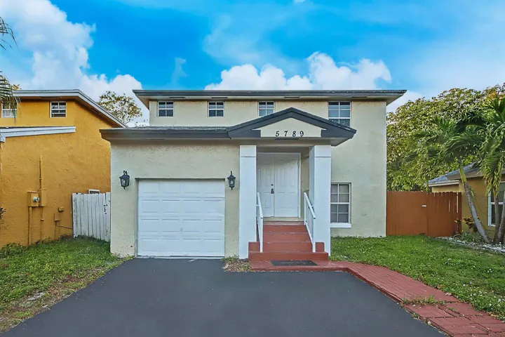 Two-story stucco exterior featuring a covered entry, white double doors, and a single-car garage