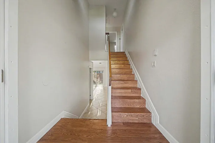 Hardwood flooring extends from the entryway, transitioning to a full staircase with wood treads and white risers