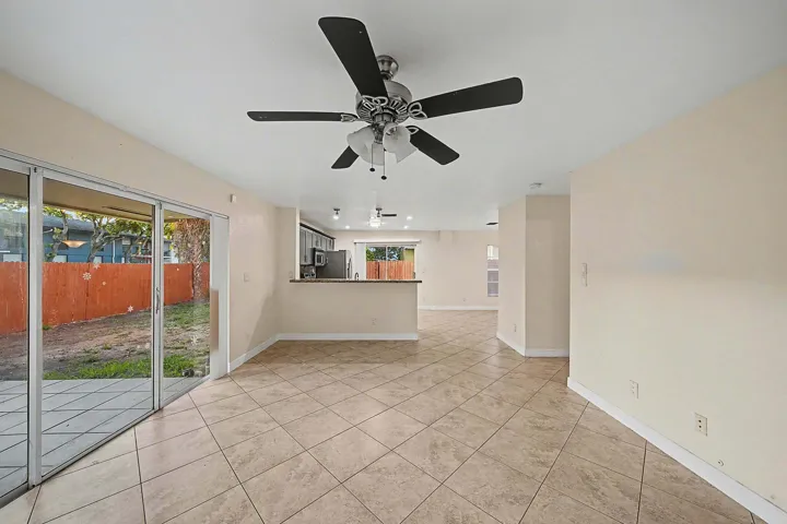 Spacious interior featuring neutral wall tones, large format tile flooring, and a ceiling fan with light fixture