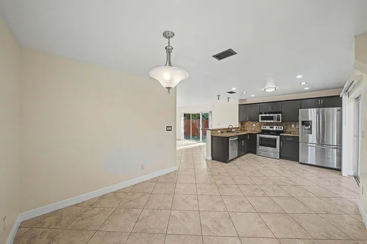 Spacious kitchen featuring dark cabinetry, stainless steel appliances, granite countertops, and a tile backsplash
