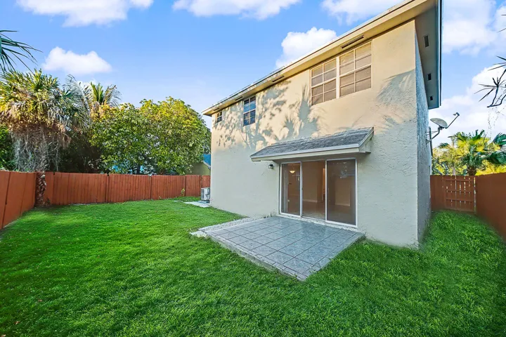 Expansive grassy backyard featuring a tiled patio and sliding glass doors