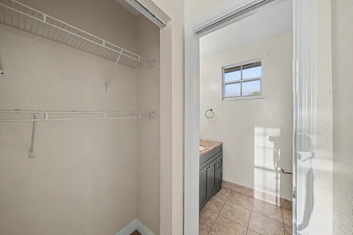 Bright bathroom featuring a window, tile flooring, and a vanity with a stone countertop