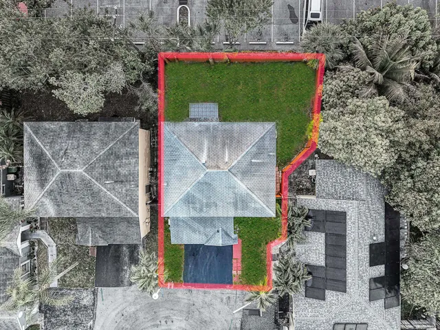 Aerial perspective highlighting a residential property with a gabled roof and surrounding green space