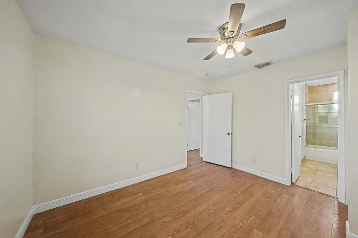 Room featuring wood-finish flooring, a ceiling fan with integrated lighting, and light-toned walls