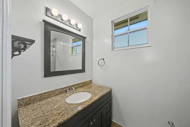 Bathroom vanity featuring a speckled countertop, integrated sink, and dark wood-finish cabinetry