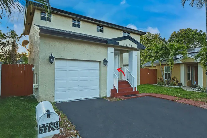 Two-story stucco exterior featuring a covered entry, white garage door, and a paved driveway