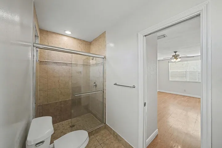 Bathroom featuring a tiled standing shower with a glass enclosure, a white toilet, and recessed lighting